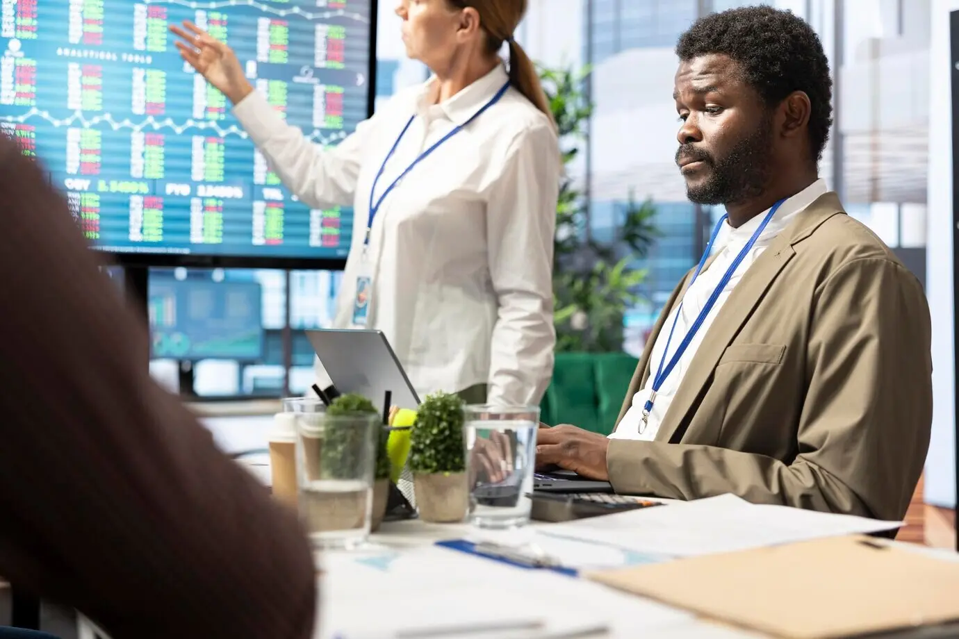 Разнообразная команда руководства оценивает бюджетные отчеты на интерактивной доске.